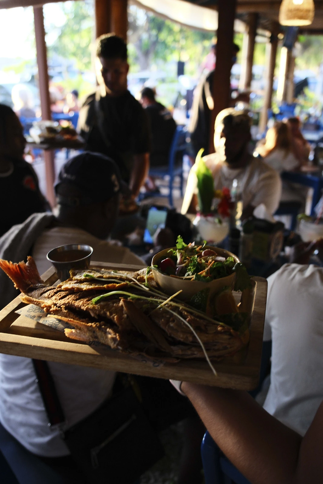 Mesero de Cocos Beach Front sirviendo tabla de pescado entero al comedor